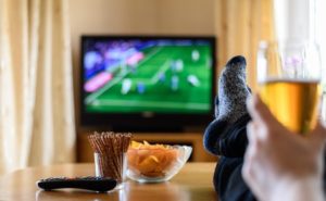 39302351 - television, tv watching (football match) with feet on table and huge amounts of snacks - stock photo